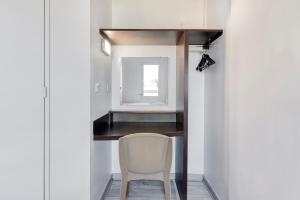 a white chair in a room with a mirror at Fasthotel Angers Beaucouzé in Beaucouzé