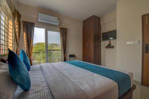 a bedroom with a bed with blue pillows and a window at AVN Comforts Mysore in Mysore +78 photos