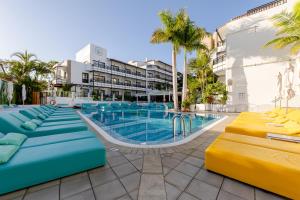 a pool at a resort with blue and yellow chairs at Vanilla Garden Boutique Hotel - Adults Only in Playa de las Americas