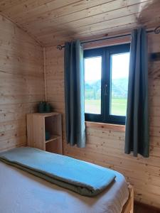 a bedroom with a bed and a window with blue curtains at La roulotte des foins in Montmaur