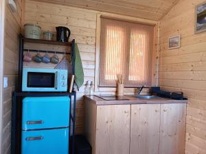 a kitchen with a blue refrigerator and a microwave at La roulotte des foins in Montmaur +4 photos