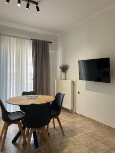 a dining room with a table and chairs and a television at Elonia Apartment in Polygryos