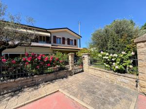 a house with a fence with pink roses at Alla Stella B&B in Vo Euganeo