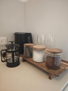a shelf with jars and wine glasses on a counter at michal Cozy Garden Unit & Jacuzzi in Kammon