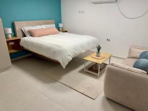 a bedroom with a bed and a couch and a table at michal Cozy Garden Unit & Jacuzzi in Kammon