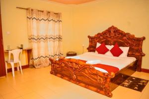 a bedroom with a large wooden bed with red pillows at Homebase gardens guesthouse in Nakuru