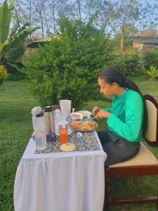 a woman sitting at a table with a plate of food at Homebase gardens guesthouse in Nakuru
