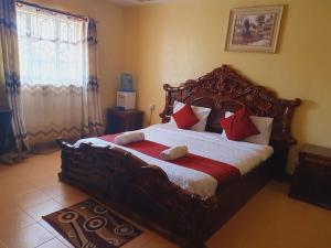 a bedroom with a large wooden bed with red pillows at Homebase gardens guesthouse in Nakuru