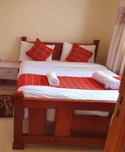 a bed with red and white pillows on it at Homebase gardens guesthouse in Nakuru +97 photos