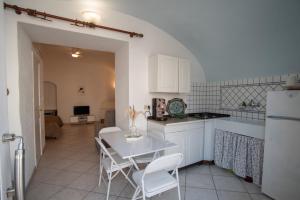 a kitchen with white cabinets and a table and chairs at Casa trani in Ischia