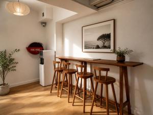 a kitchen with a bar with stools and a refrigerator at Wink at Jalan Besar in Singapore
