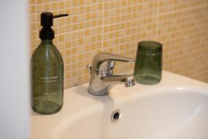 a bathroom sink with a green bottle and a soap dispenser at Casa trani in Ischia +19 photos