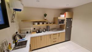 a kitchen with wooden cabinets and a stainless steel refrigerator at شقق ضيافة خاصه خدمة ذاتية in Buraydah