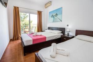 a hotel room with two beds and a balcony at Andronis in Potos