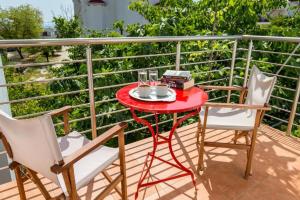 a red table and two chairs on a balcony at Andronis in Potos +7 photos