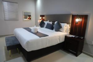 a bedroom with a large white bed with a night stand at Dikukama Executive Hotel in Tshabong