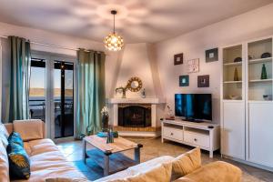 a living room with a couch and a tv at Aegean Verde Retreat in Sounio