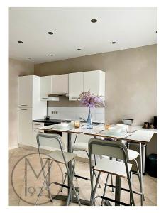 a kitchen with white cabinets and a table with chairs at Maison 1925, Méricourt 62 in Méricourt