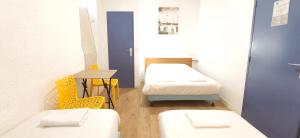 a room with two beds and a table and yellow chairs at Hôtel Duchesse Anne in Lourdes