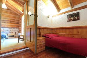 a bedroom in a log cabin with a red bed at Baita Costa Di Gial in Lamon