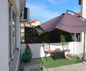 eine Terrasse mit zwei Stühlen und einem Sonnenschirm in der Unterkunft Studio Perina in Trogir