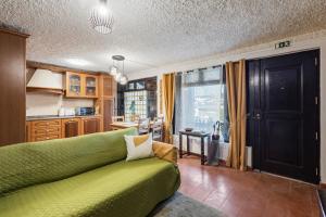 a living room with a green couch and a kitchen at Banyan Tree in Óbidos