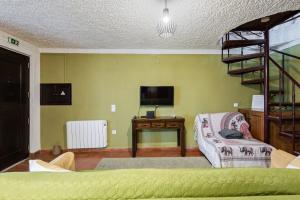 a living room with a spiral staircase and a television at Banyan Tree in Óbidos +13 photos