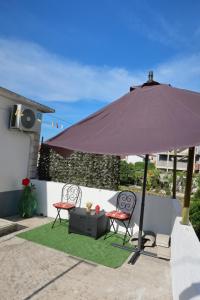 ein lila Sonnenschirm, zwei Stühle und ein Tisch in der Unterkunft Studio Perina in Trogir + 6 Fotos