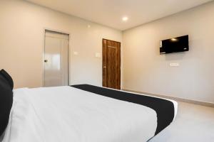 a bedroom with a white bed and a flat screen tv at Super Collection O RBS ECIL in Hyderabad