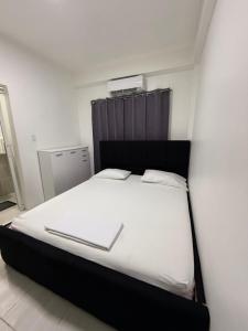 a bedroom with a white bed with a black headboard at HHC Apartments Kronos in Paramaribo