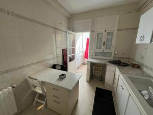 a white kitchen with a counter and a sink at La Marsa in El Aouina Station
