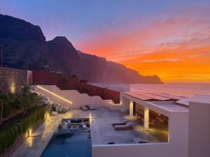 a building with a pool and the ocean at sunset at Walhalla Seahouse in Chã da Igreja