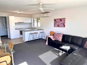 a living room with a black couch and a kitchen at Sunny Shackell - family and pet friendly in Echuca