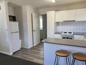 a kitchen with white cabinets and a counter with stools at Sunny Shackell - family and pet friendly in Echuca