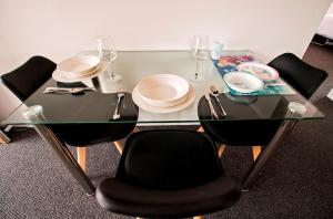a glass table with chairs and plates and wine glasses at Sunny Shackell - family and pet friendly in Echuca +10 photos
