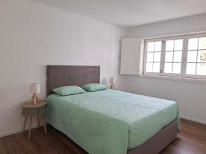 a white bedroom with a bed and a window at 4-As Andar-Moradia Muralhas in Guimarães