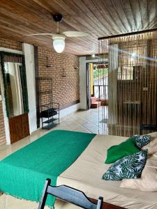 a bedroom with a large bed with a green blanket at Flats na praia de Trindade Paraty flats nazar in Paraty