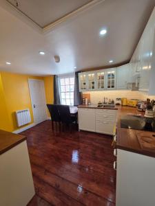 a kitchen with white cabinets and a wooden floor at The Salty Loft in Hastings