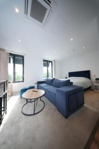a living room with a blue couch and a table at HDG Hôtel Gare de L'Isle Adam Appart's Hotel in Parmain