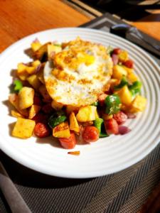 a white plate of food with an egg and vegetables at Kilimanjaro Magic MJ Branch in Old Moshi