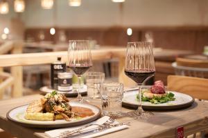 a table with two plates of food and glasses of wine at Bretterbude Büsum in Büsum
