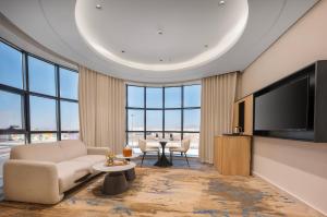 a living room with a couch and a tv and a table at Ayas Hail Hotel - فندق أياس حائل in Hail