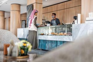 a man and a woman standing at a counter at Ayas Hail Hotel - فندق أياس حائل in Hail