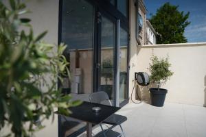 a patio with a table and a phone on the side of a building at HDG Hôtel Gare de L'Isle Adam Appart's Hotel in Parmain