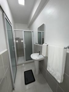 a white bathroom with a sink and a shower at HHC Apartments Kronos in Paramaribo +12 photos