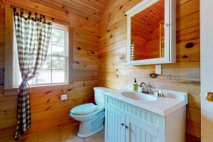 a bathroom with a toilet and a sink in a log cabin at Leavitt Bay Shores in Ossipee