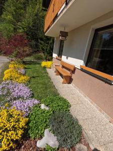 a garden with a bench and flowers in front of a building at Holiday Home Forest Peace, Lavrovec in Hlevni Vrh