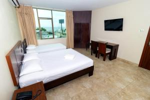 a bedroom with a bed and a desk and a television at Hotel Marvento Suites in Salinas +33 photos