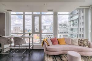 a living room with a couch and a large window at CN Tower Views - 2BR Condo - Balcony - Fast Wi-Fi in Toronto