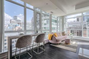 a living room with a table and chairs and windows at CN Tower Views - 2BR Condo - Balcony - Fast Wi-Fi in Toronto
